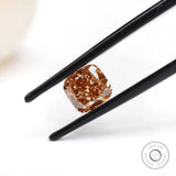 Fancy orange cushion lab diamond tilted between black tweezers
