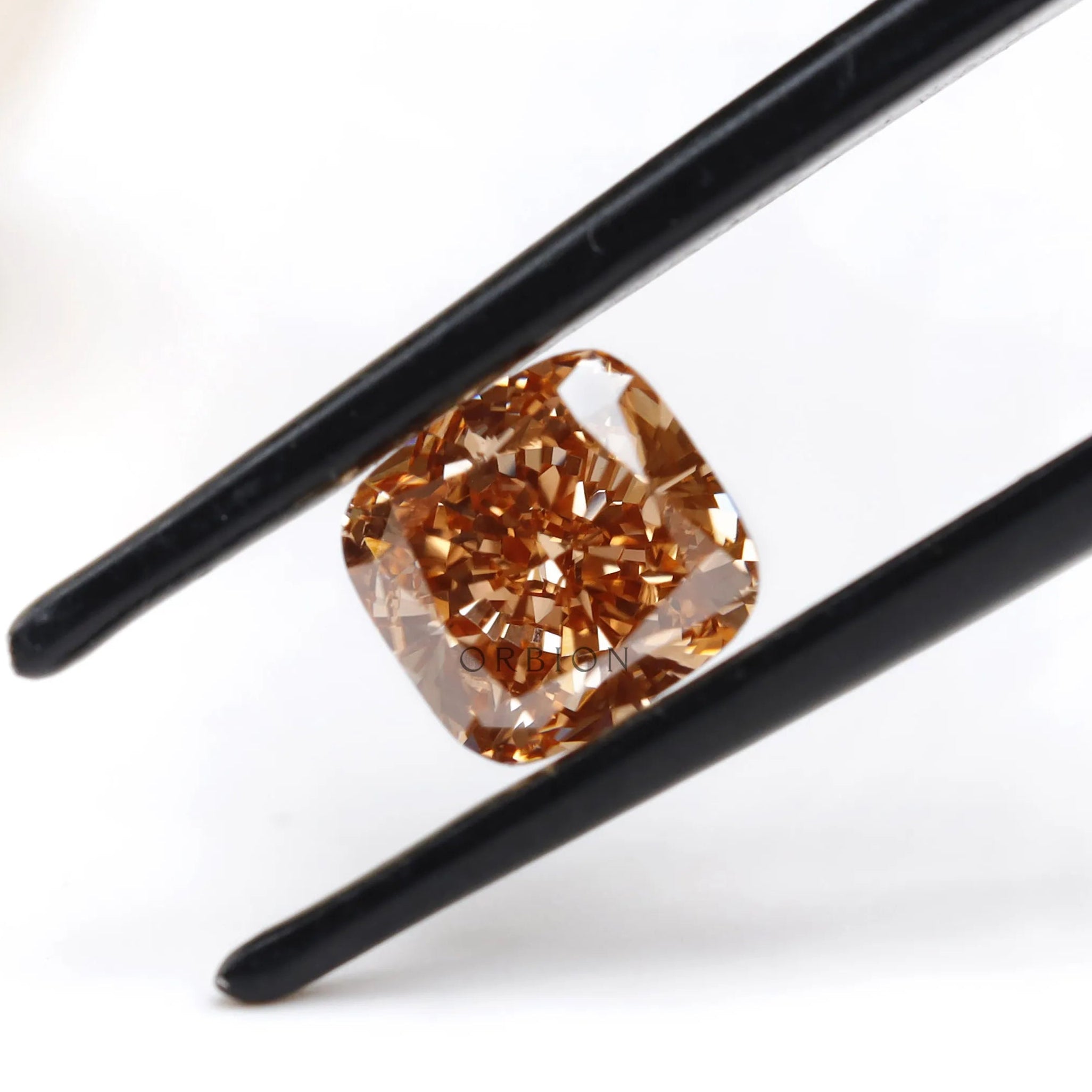 Fancy orange cushion lab diamond tilted between black tweezers
