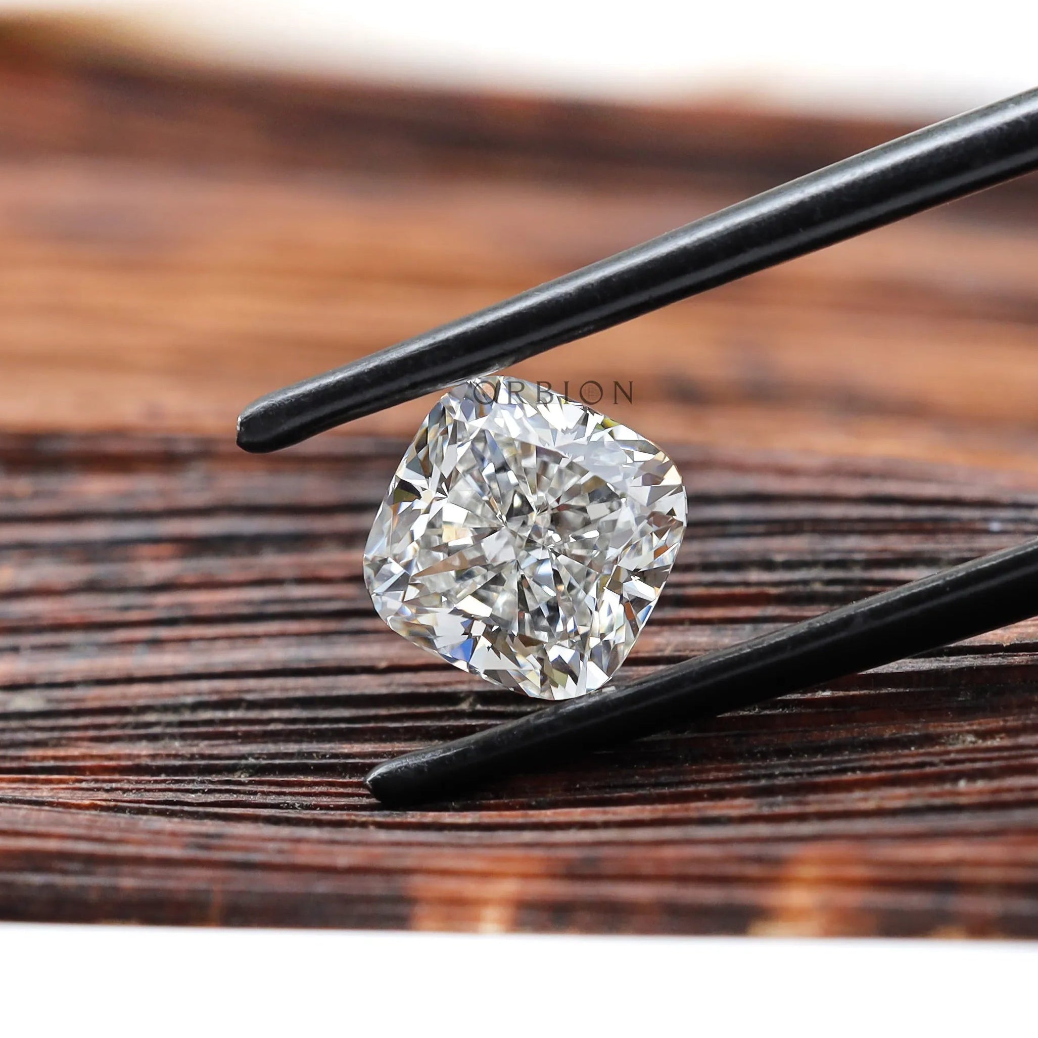 Side angled cushion brilliant diamond held with tweezers