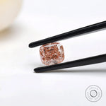 Side angled fancy pink elongated cushion diamond in tweezers
