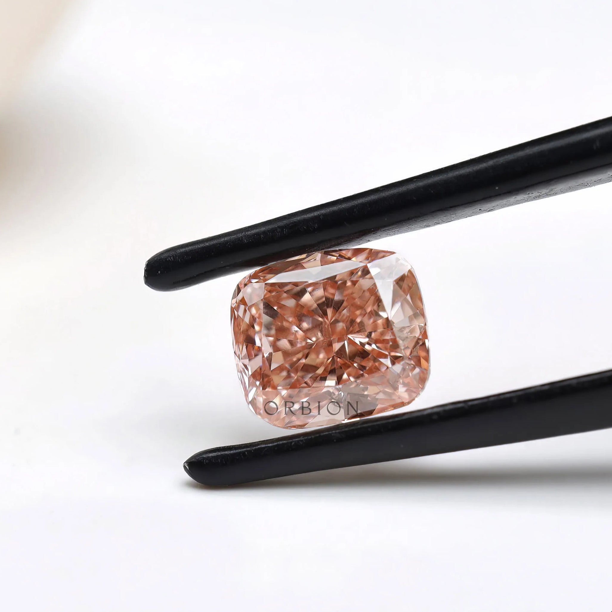 Side angled fancy pink elongated cushion diamond in tweezers
