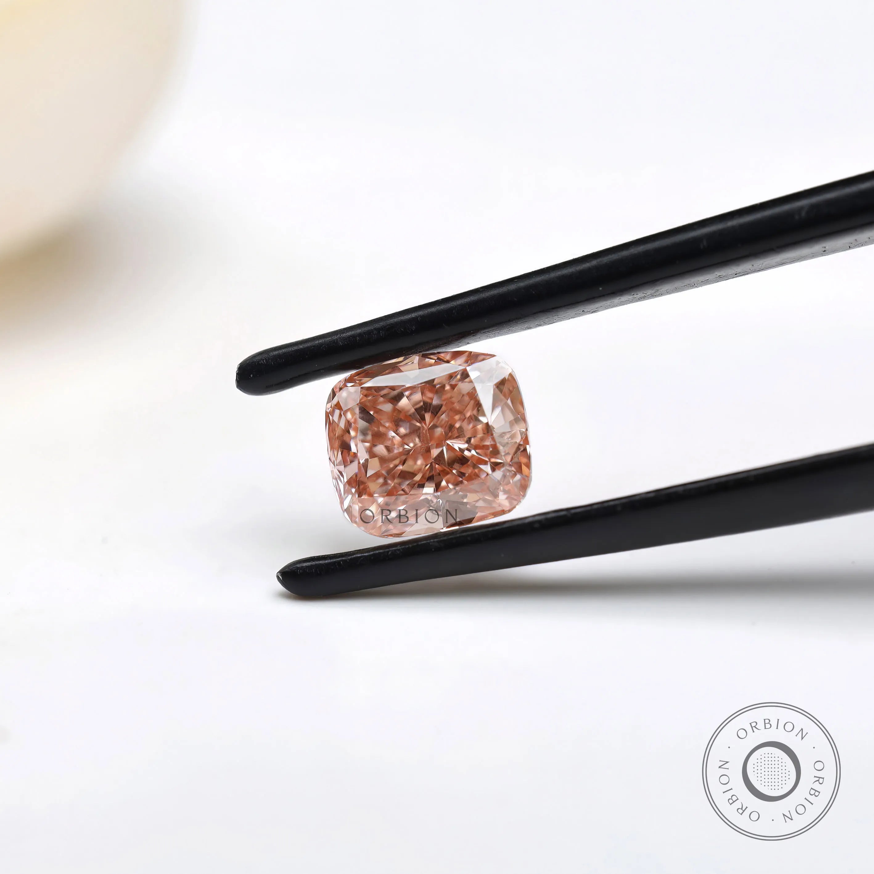 Side angled fancy pink elongated cushion diamond in tweezers
