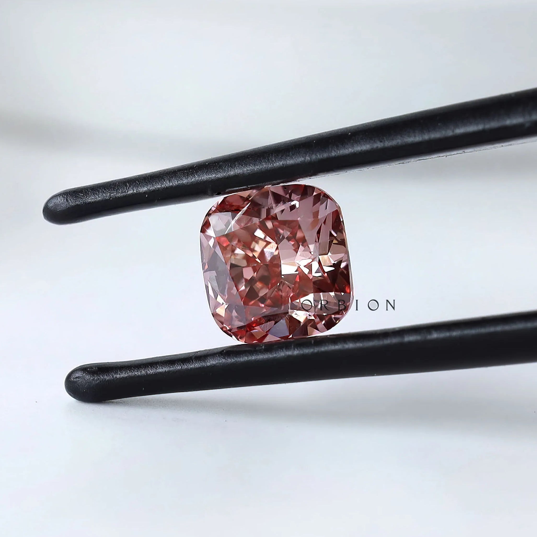 Soft square cushion pink lab diamond held in tweezers