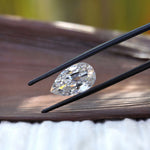 Horizontal pear old mine cut moissanite in tweezers