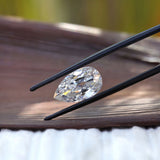 Horizontal pear old mine cut moissanite in tweezers