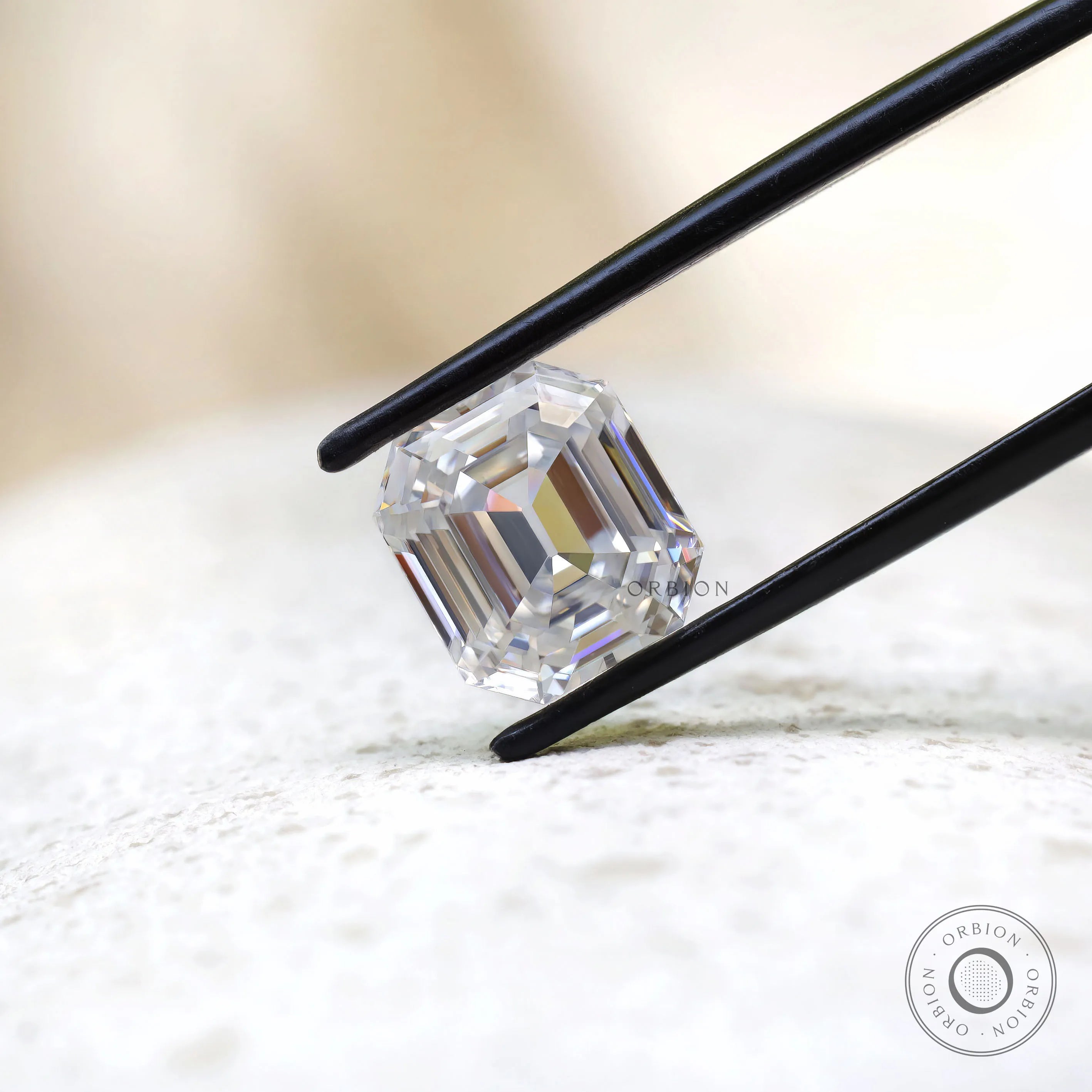 Emerald step cut moissanite displayed in black tweezers close-up