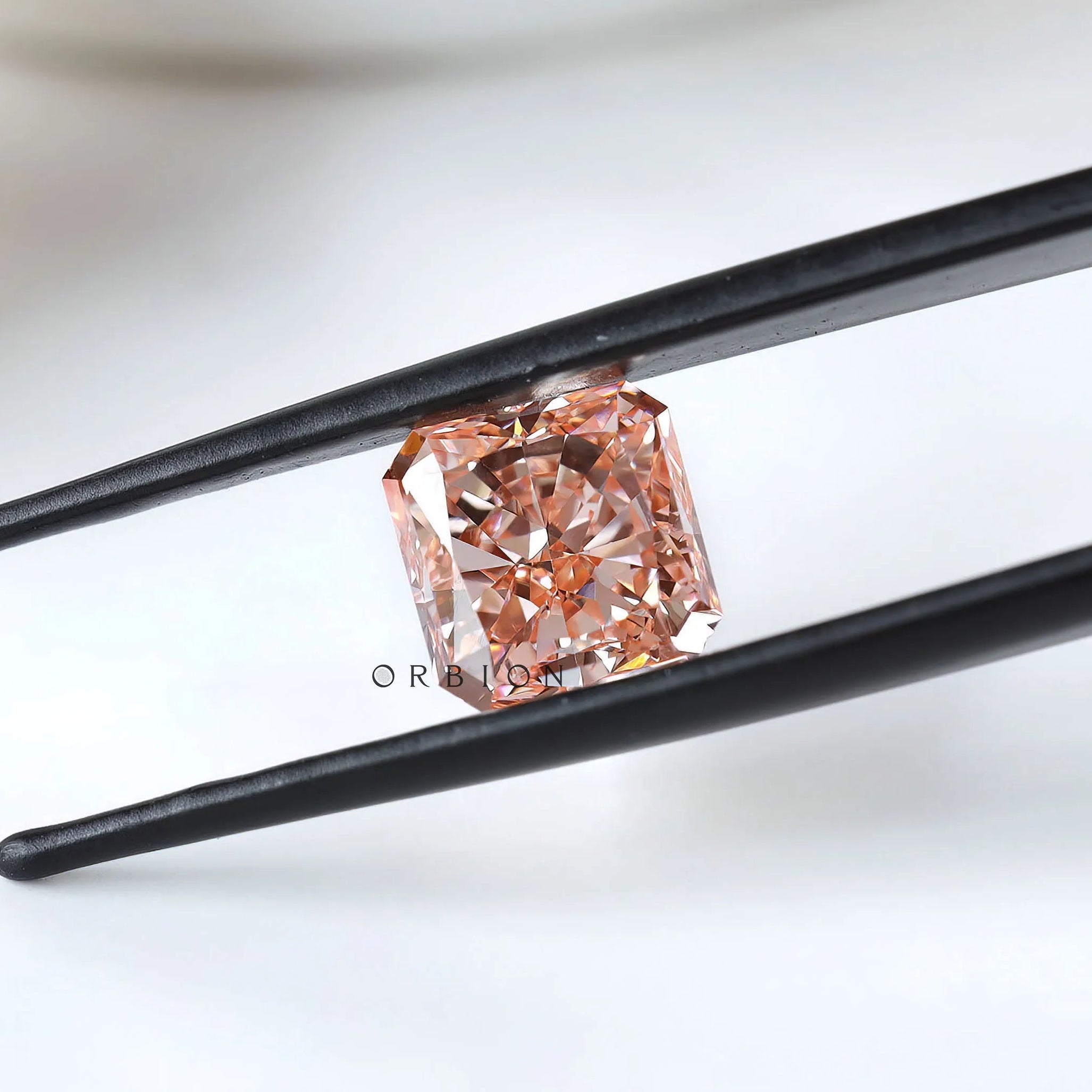 Fancy vivid pink radiant diamond held between black tweezers