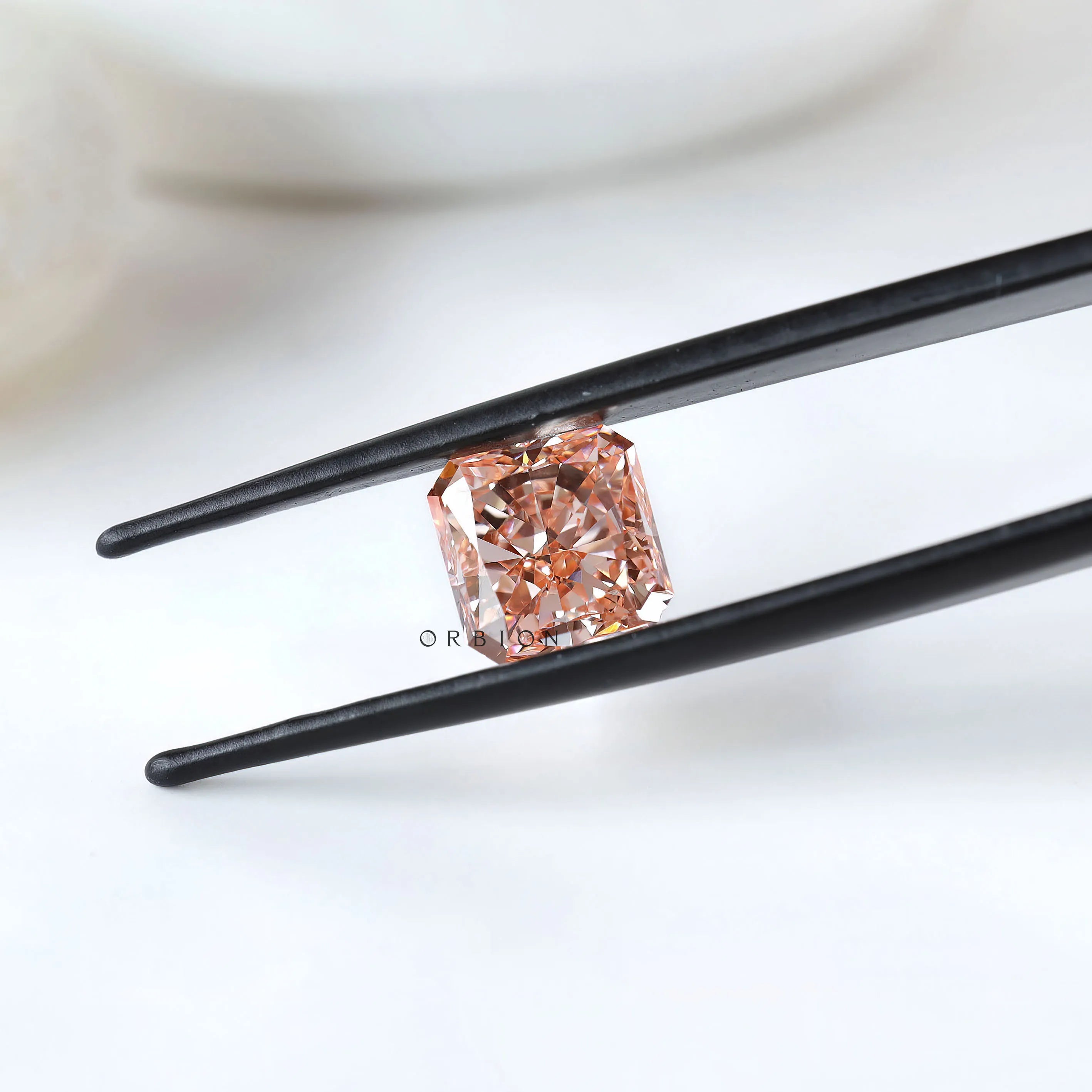 Fancy vivid pink radiant diamond held between black tweezers