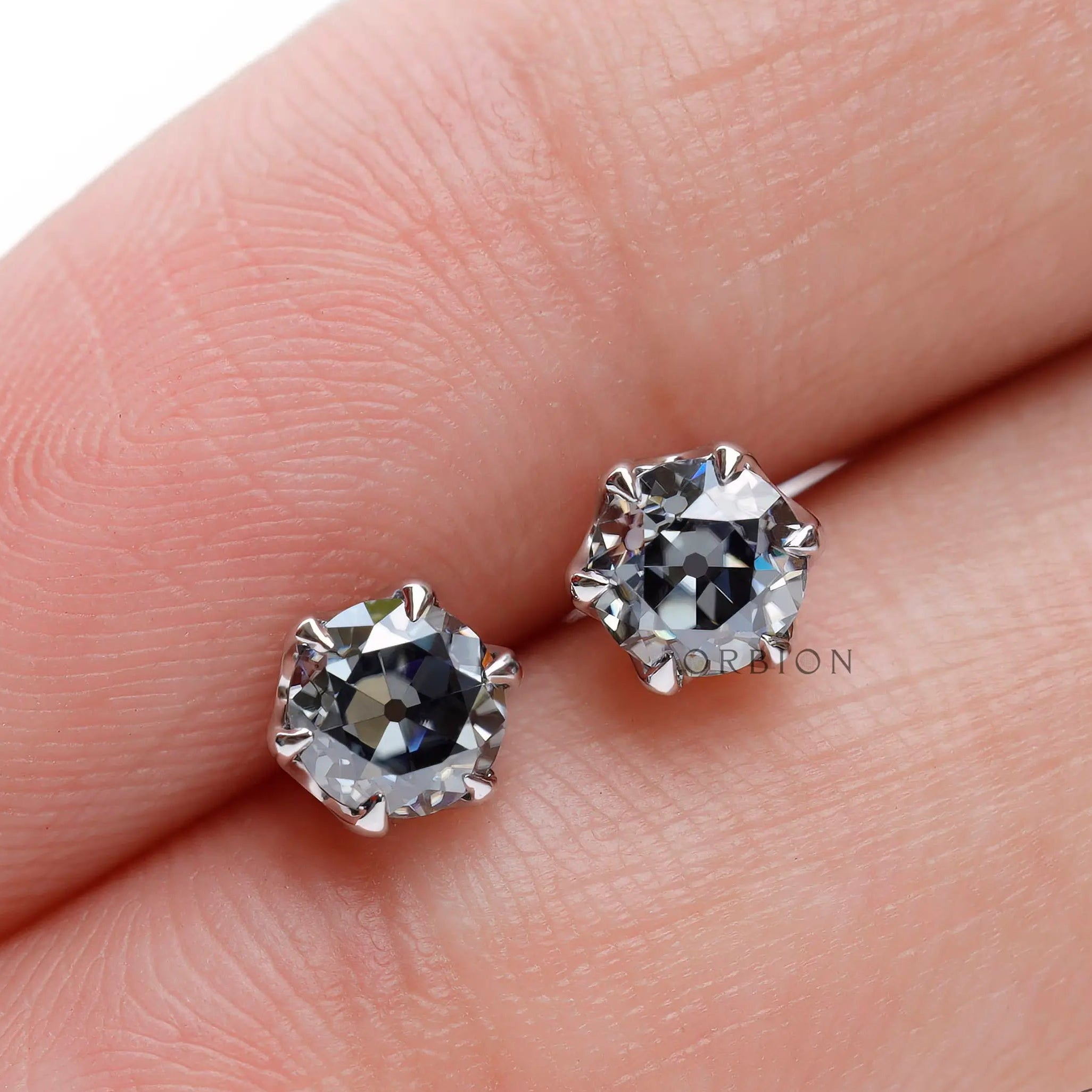 Finger scale view OEC grey moissanite stud earrings