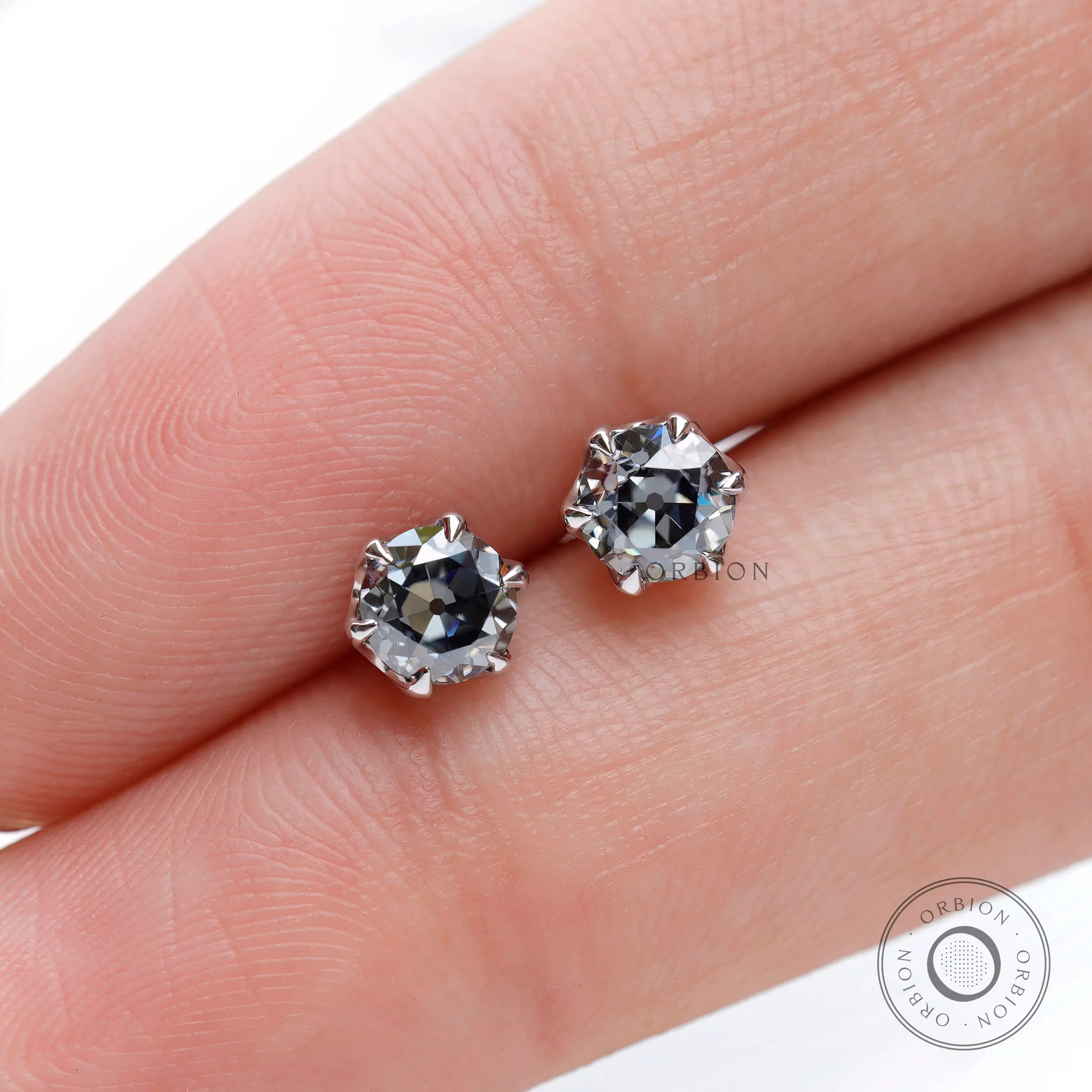 Finger scale view OEC grey moissanite stud earrings