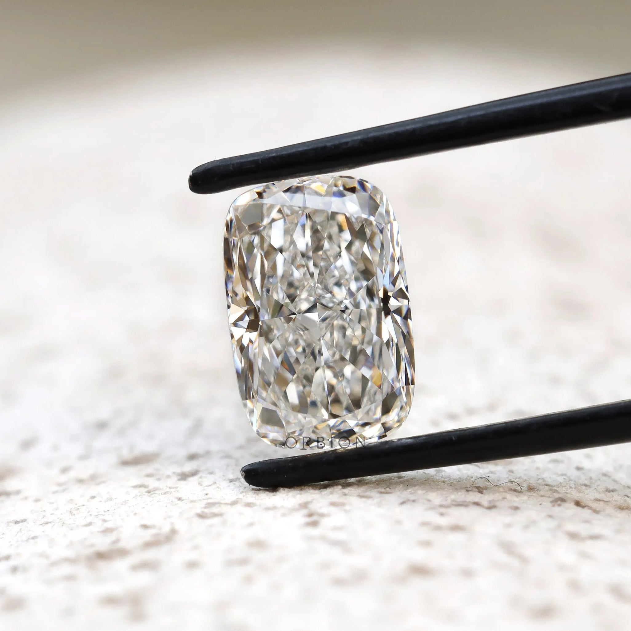 Centered elongated cushion crushed ice lab diamond in tweezers