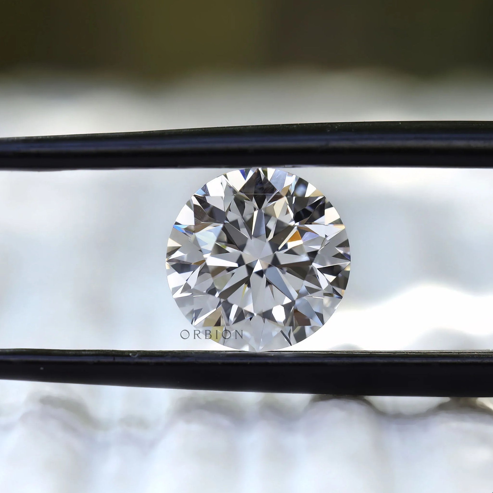 Brilliant cut round loose diamond shown in tweezers