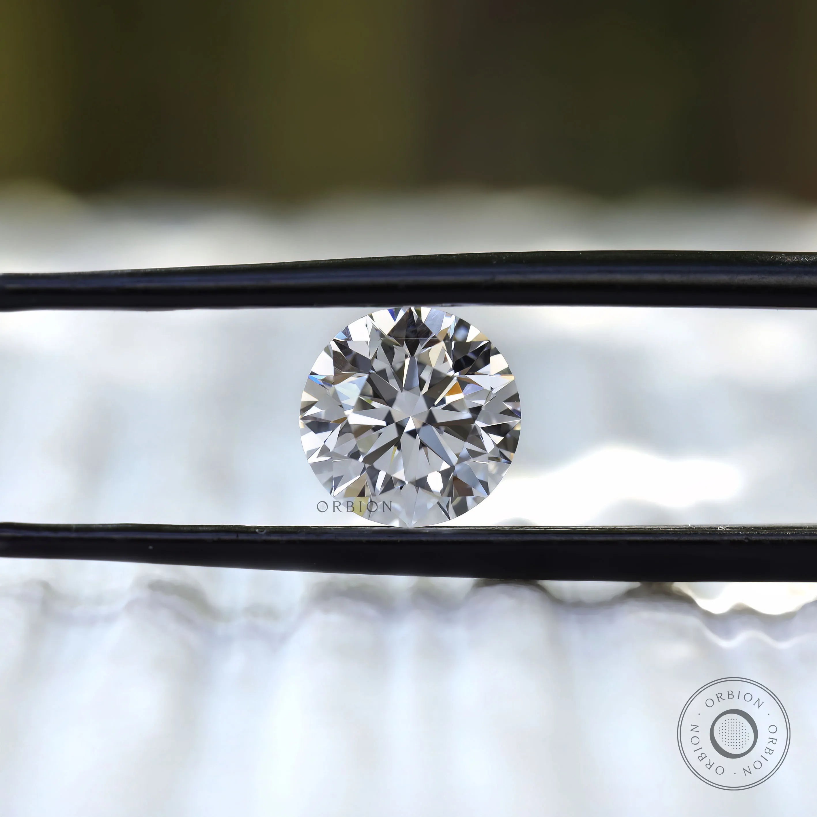 Brilliant cut round loose diamond shown in tweezers
