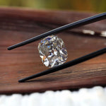 Cushion moissanite side profile on light wood surface
