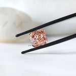 Angled radiant pink lab diamond in black tweezer display