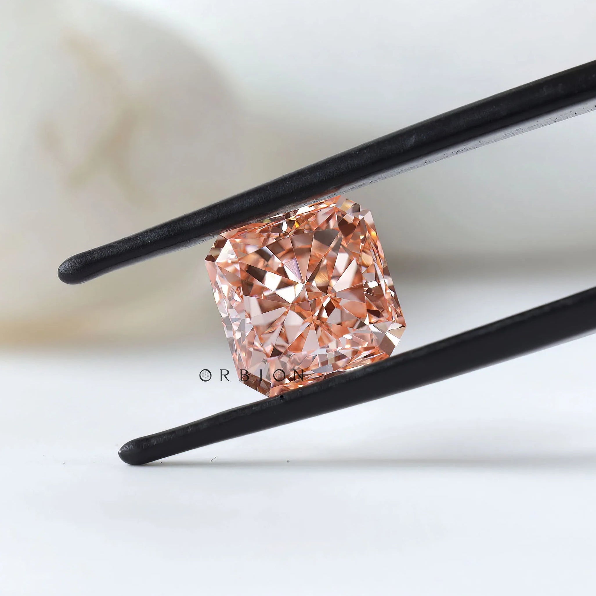 Angled radiant pink lab diamond in black tweezer display