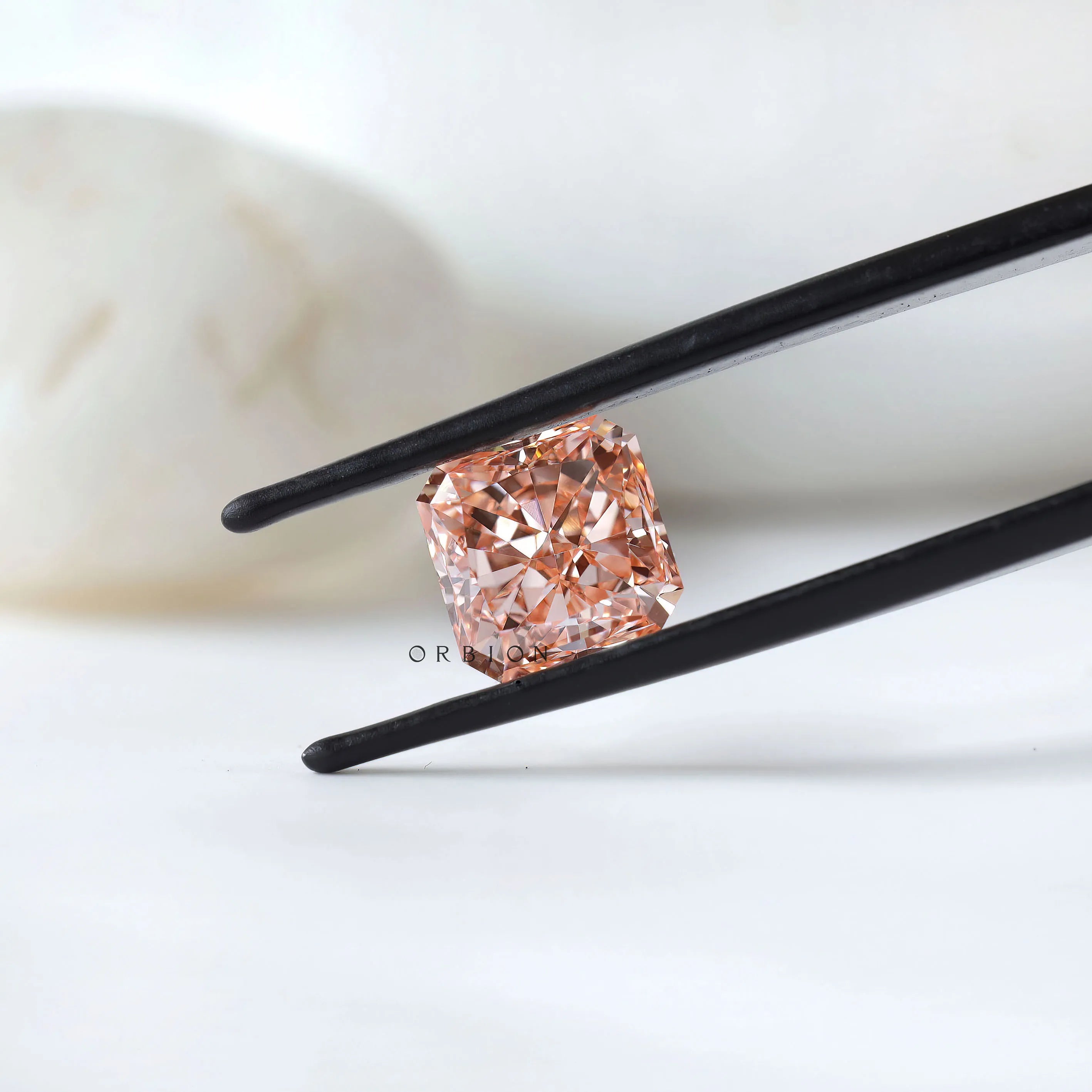 Angled radiant pink lab diamond in black tweezer display