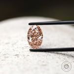 Oval pink lab diamond displayed on textured neutral background