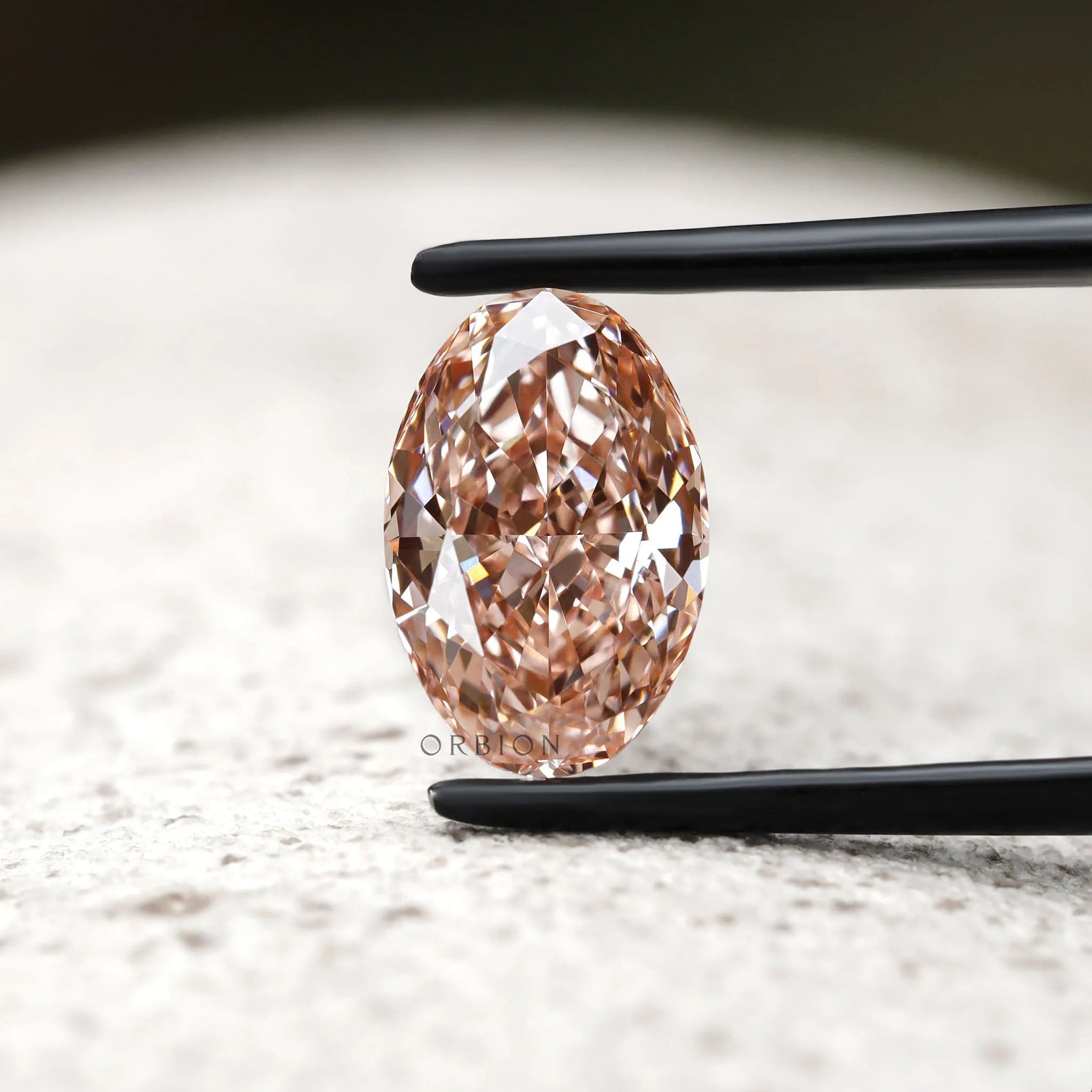 Oval pink lab diamond displayed on textured neutral background