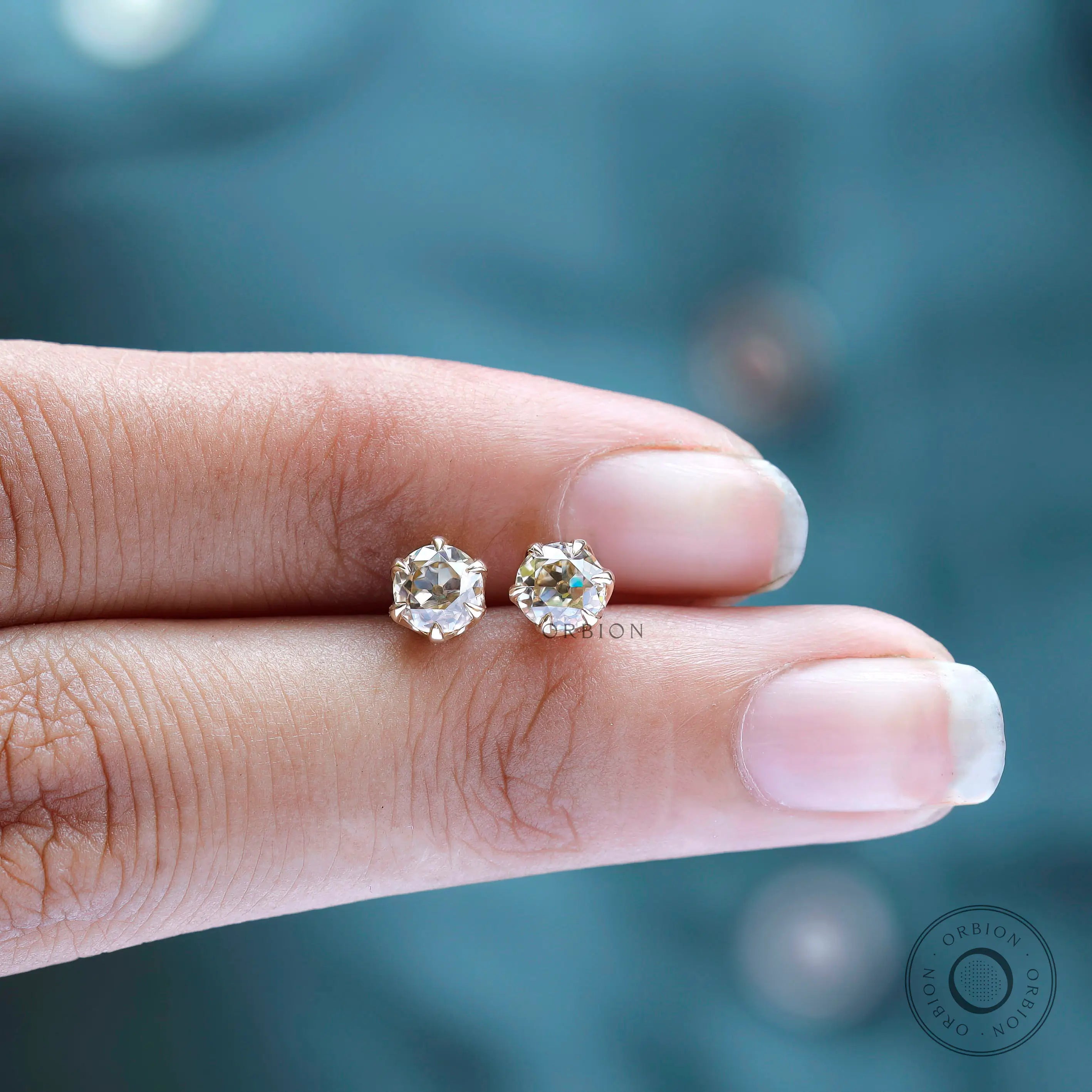 Hand scale view small champagne moissanite stud earrings gold