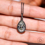 Pear moissanite pendant shown on hand for size reference