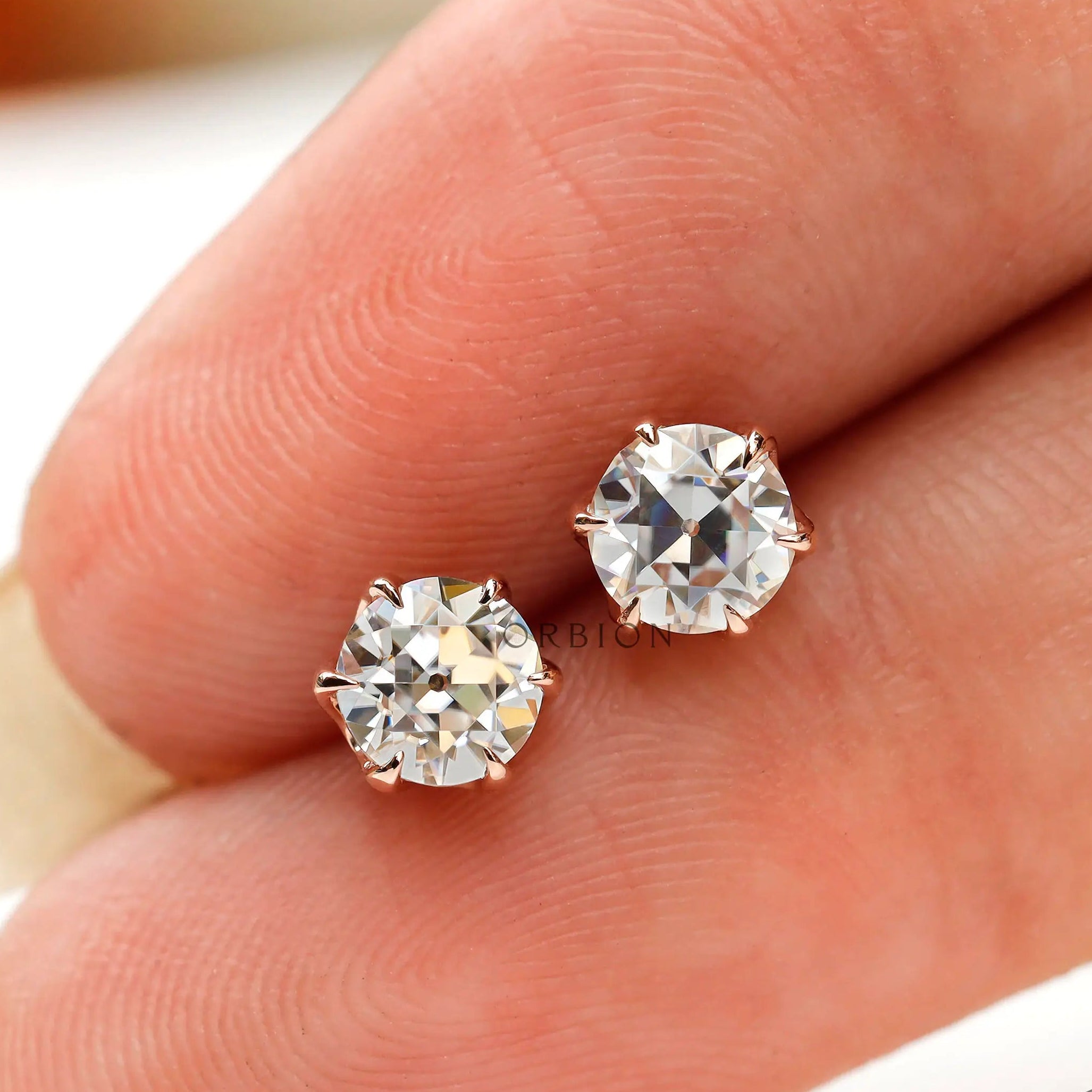 Finger scale view round moissanite rose gold studs