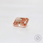 Loose fancy pink radiant diamond resting on white surface