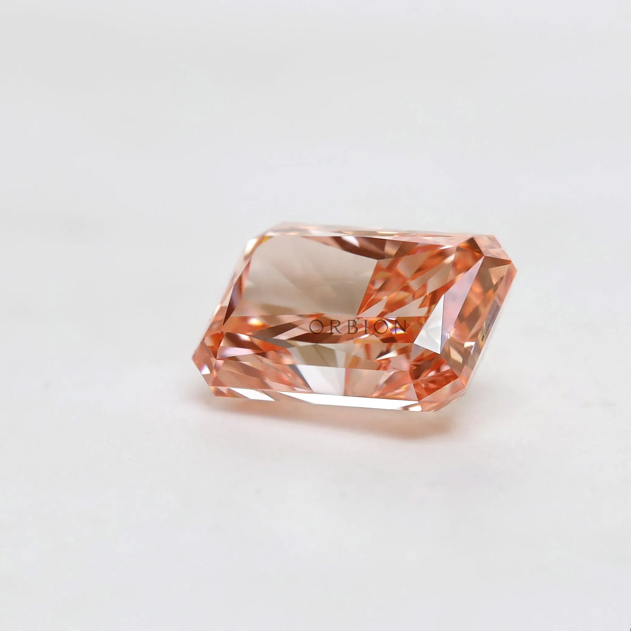 Loose fancy pink radiant diamond resting on white surface