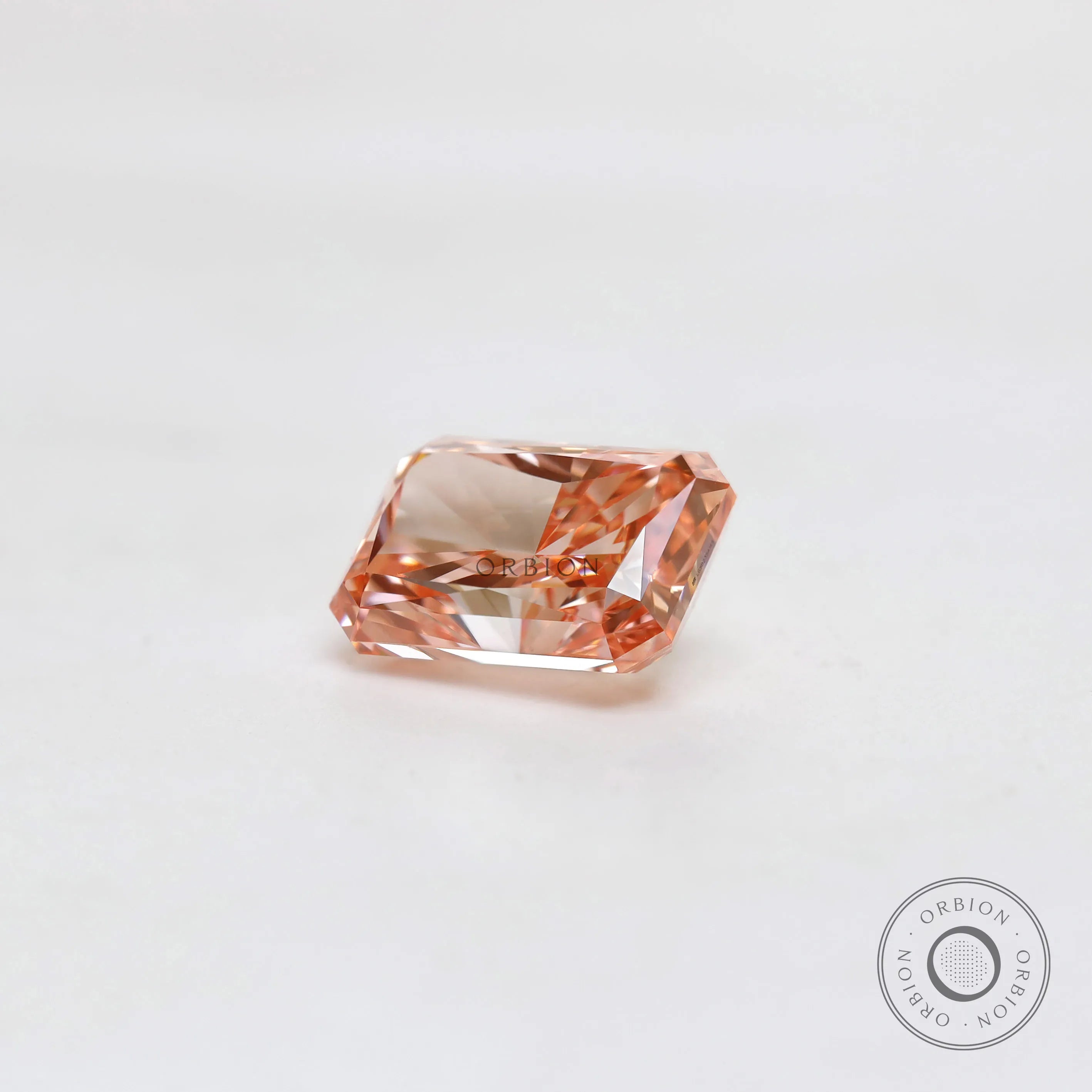 Loose fancy pink radiant diamond resting on white surface