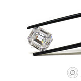 Emerald step cut loose moissanite held in tweezers on white