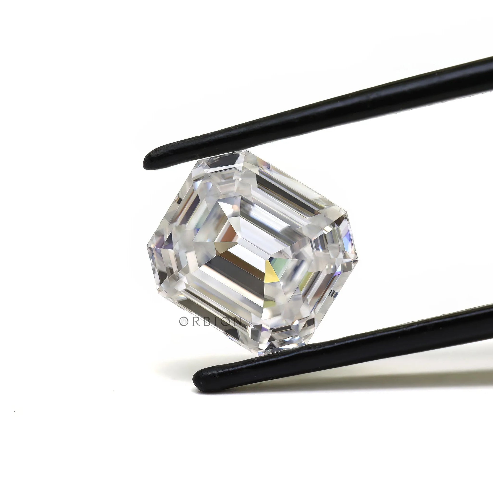 Emerald step cut loose moissanite held in tweezers on white