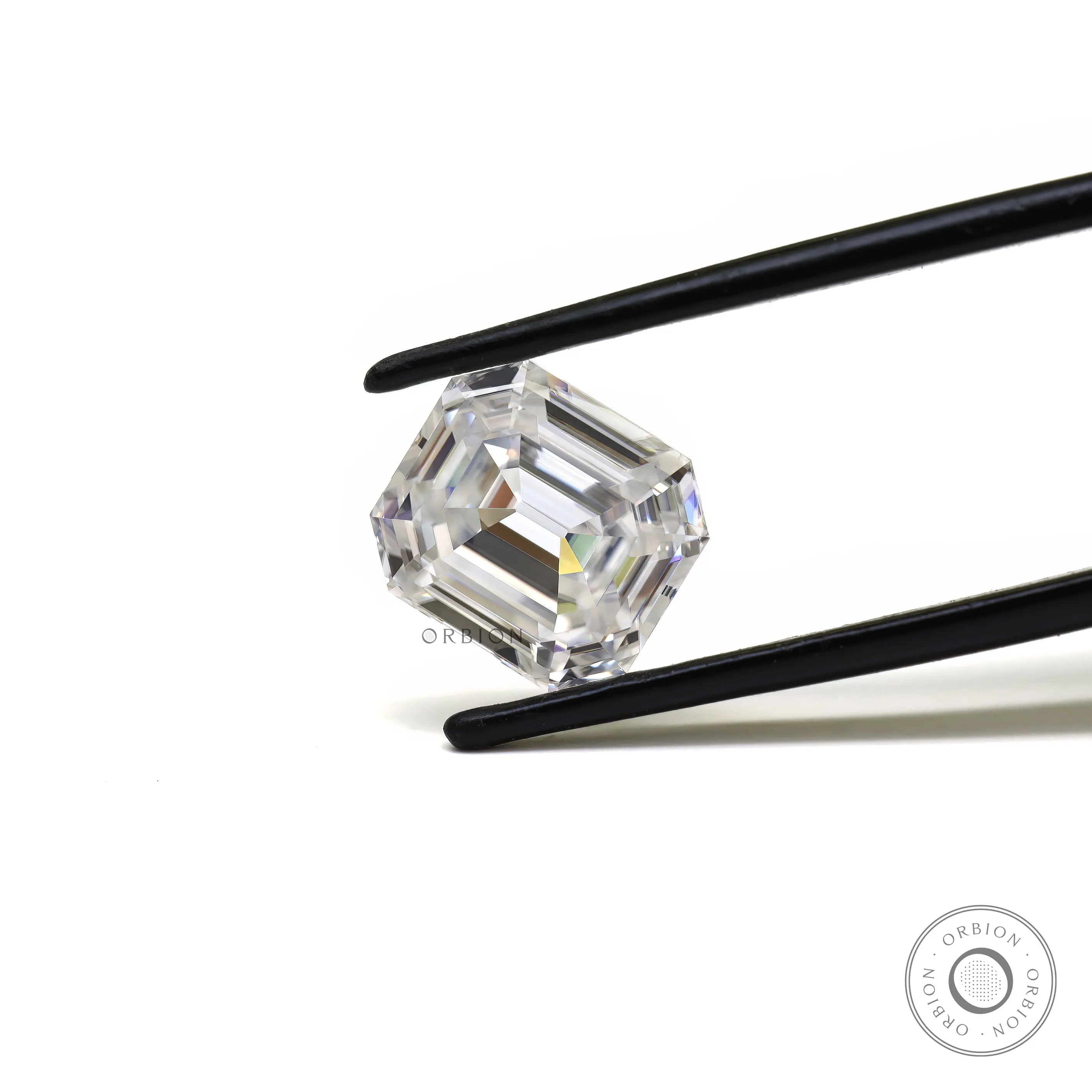 Emerald step cut loose moissanite held in tweezers on white