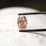 Front view of intense pink oval diamond in jeweler tweezers