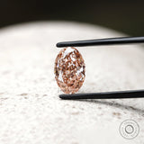 Front view of intense pink oval diamond in jeweler tweezers