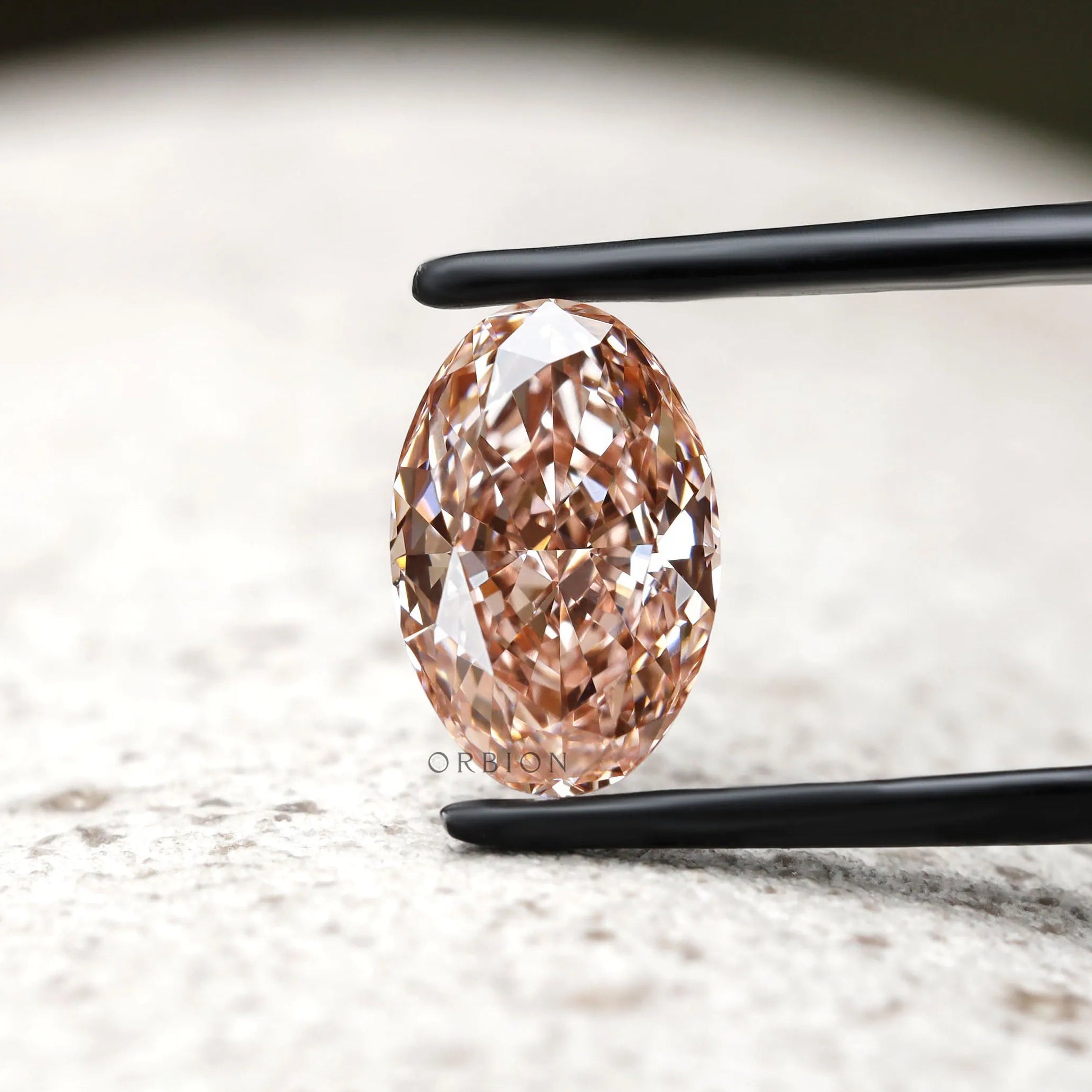 Front view of intense pink oval diamond in jeweler tweezers