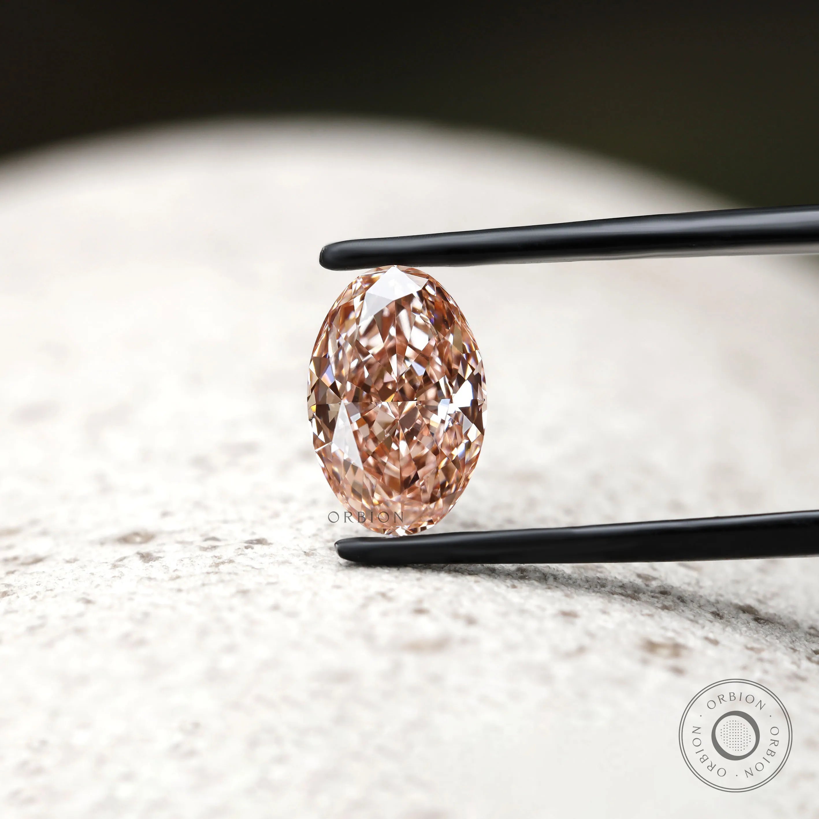 Front view of intense pink oval diamond in jeweler tweezers