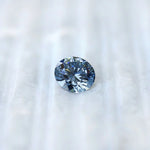 Round blue lab diamond displayed on soft white surface