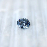 Round blue lab diamond displayed on soft white surface