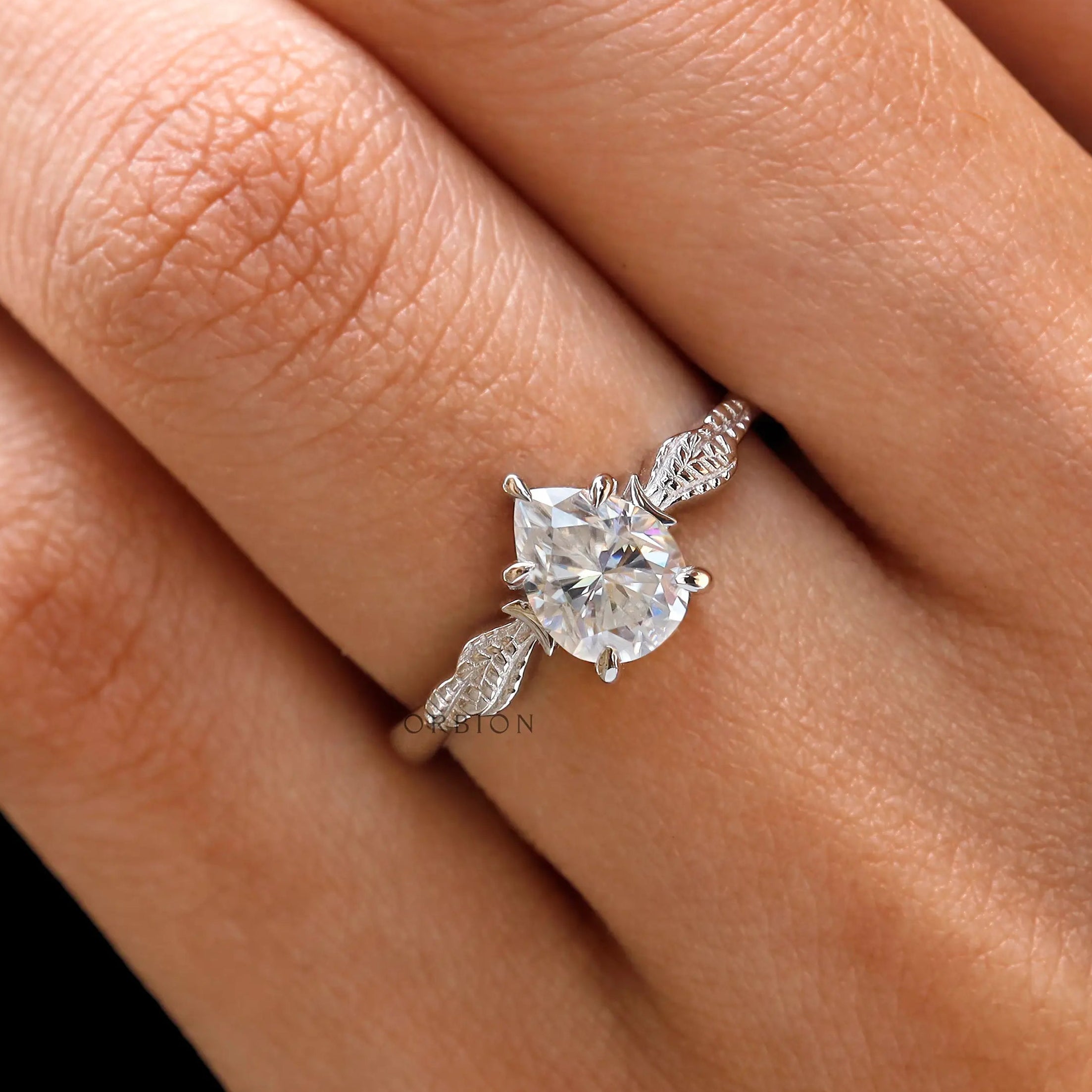 Finger view of pear Moissanite engagement ring on hand
