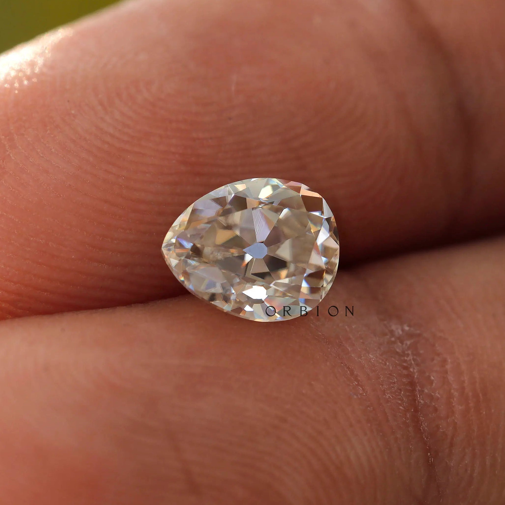 1.35 CT Old Mine Cut Moissanite Off White Pear stone in hand held