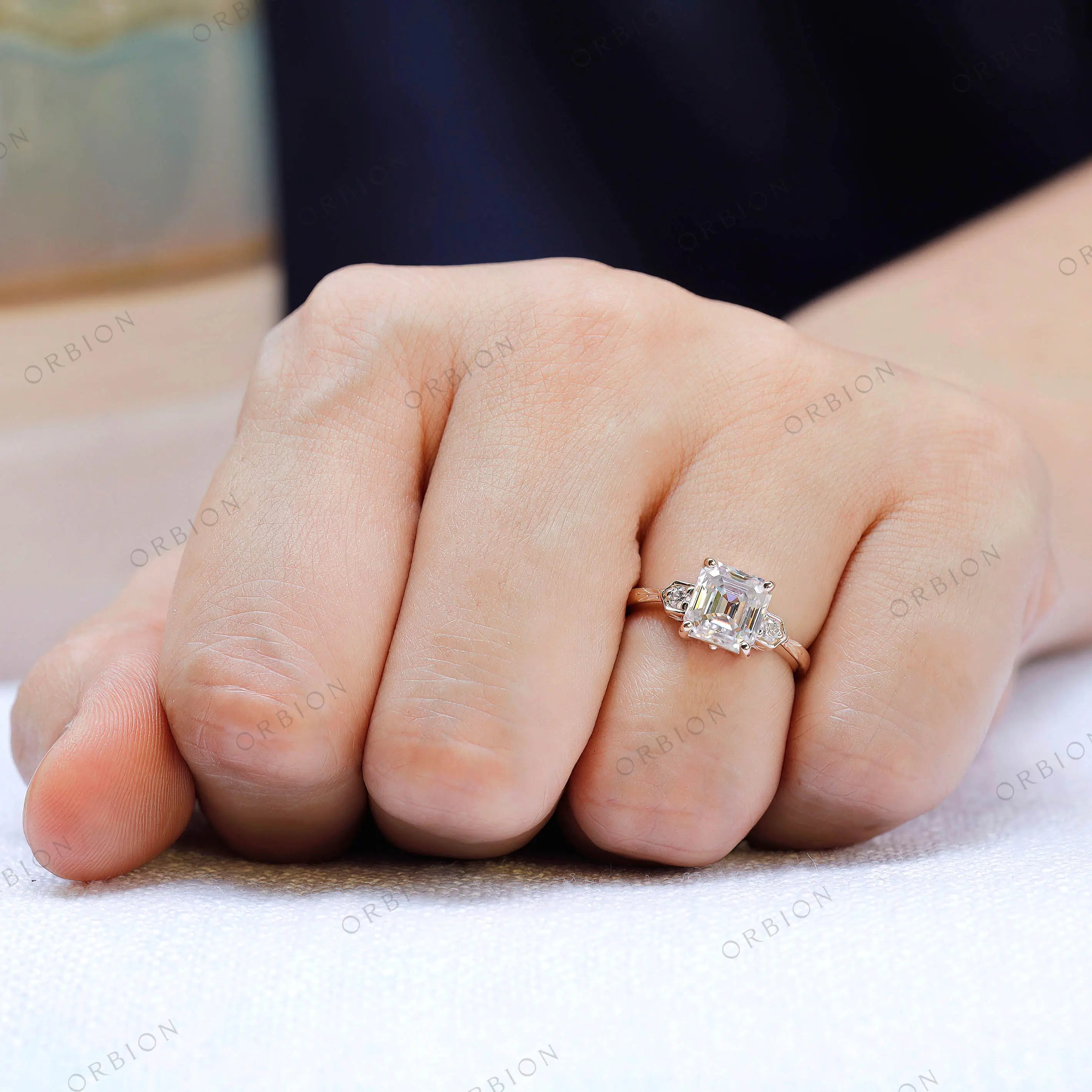 Asscher moissanite three stone ring with floral detailing on hand