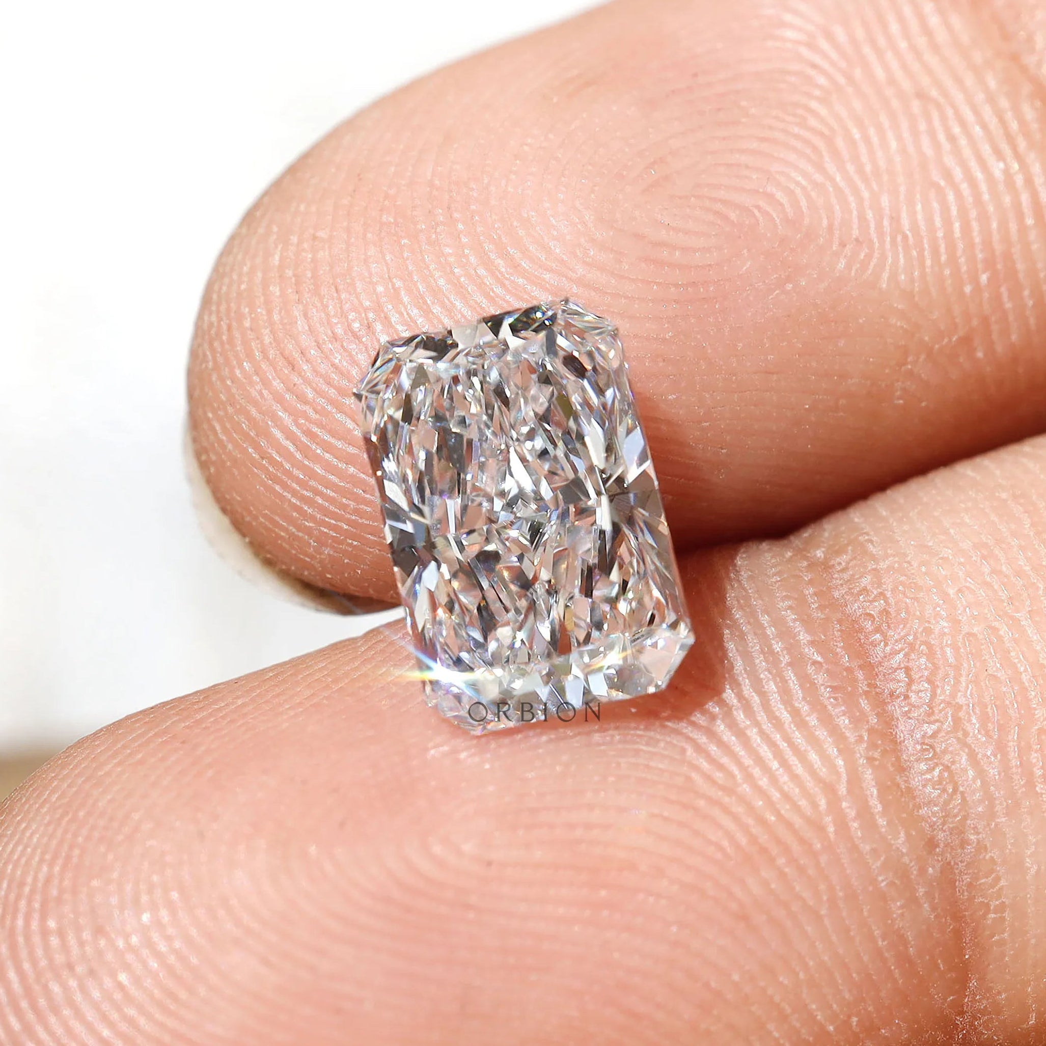Close-up of rectangular radiant cut loose lab diamond on fingertips