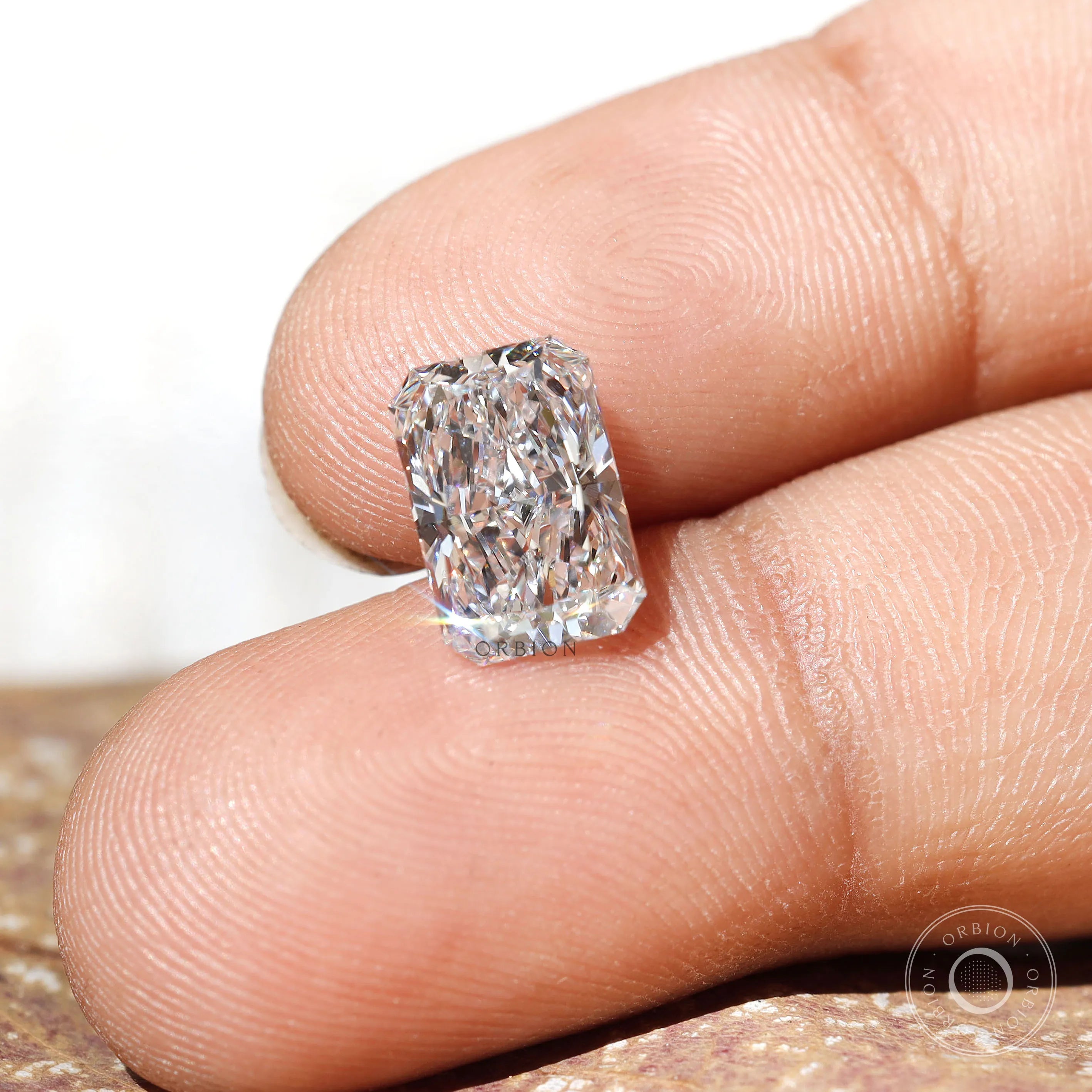 Close-up of rectangular radiant cut loose lab diamond on fingertips