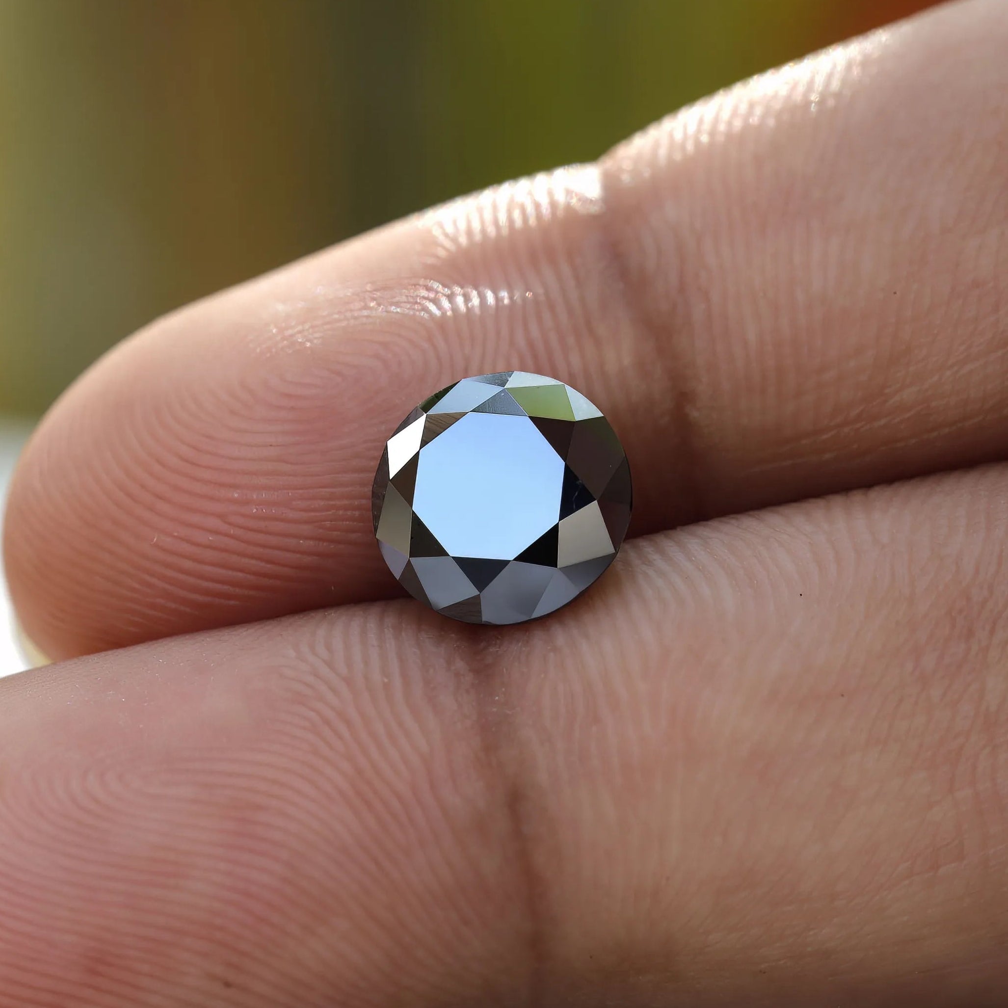 Sparkling 2 CT Round Black Moissanite stone on hand