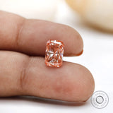 Close fingertip view of fancy pink radiant lab diamond
