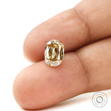 Champagne moissanite shown on fingertips in elongated cushion shape
