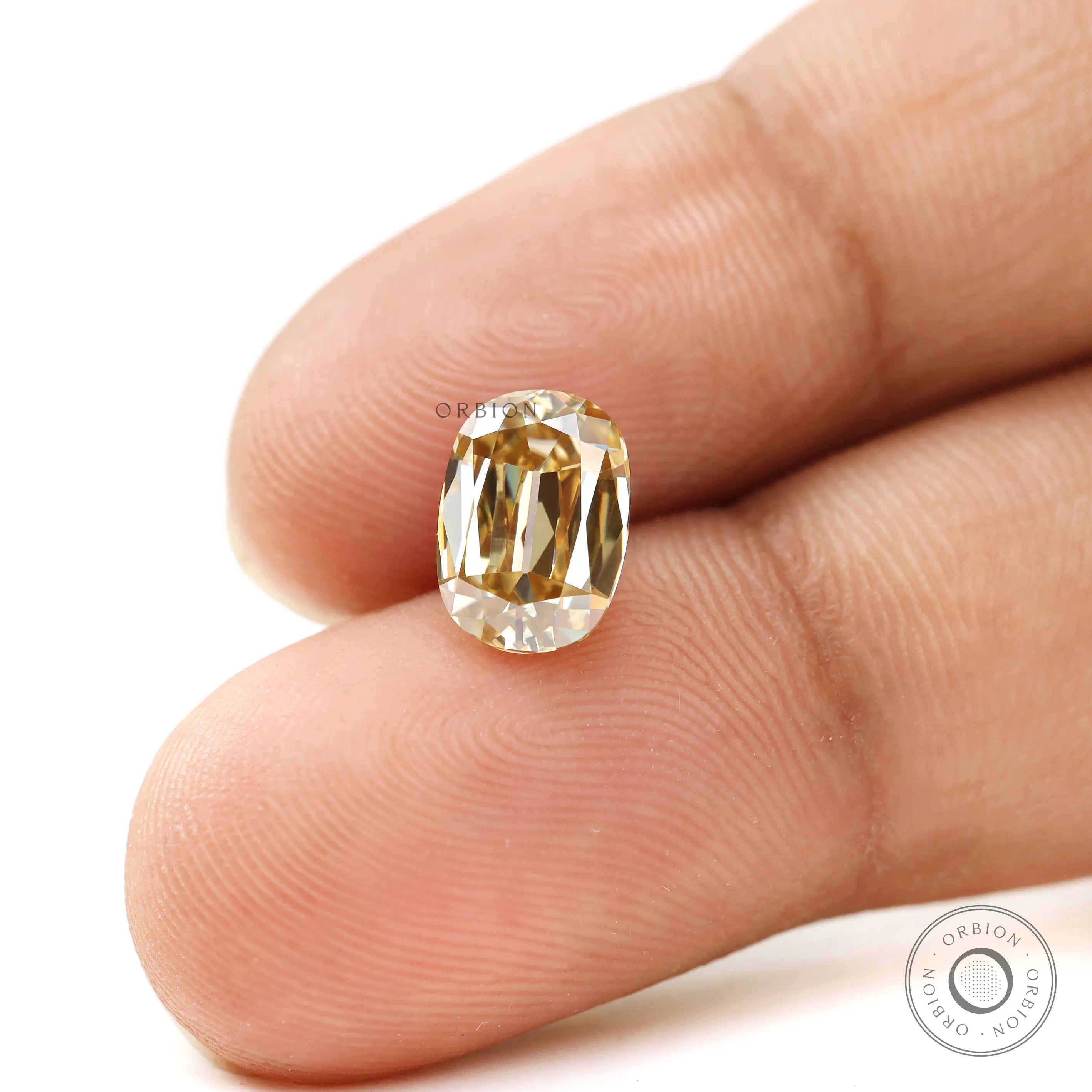 Champagne moissanite shown on fingertips in elongated cushion shape