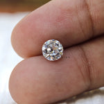 Round loose moissanite placed on fingertips for size reference