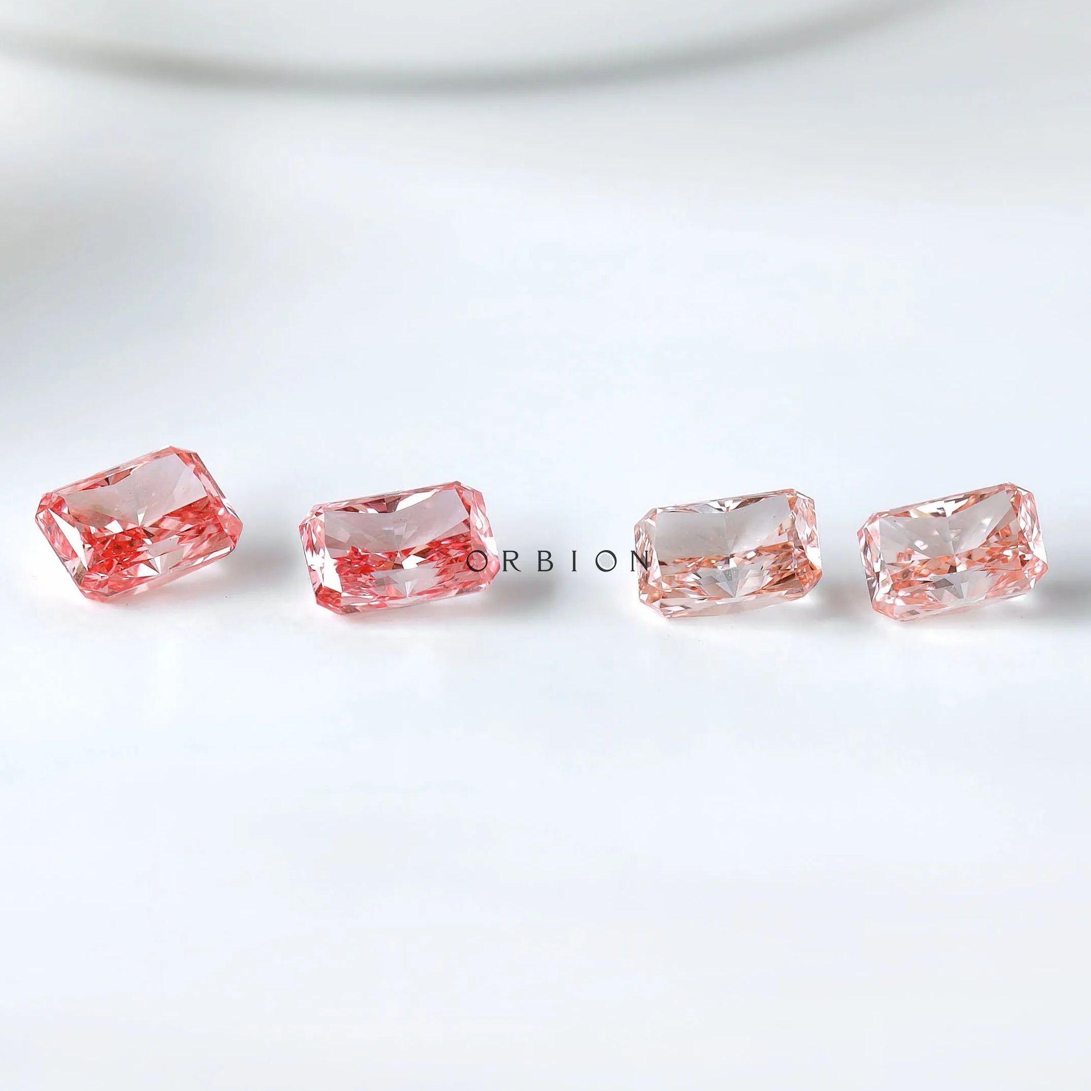 Row display of four radiant pink loose diamonds
