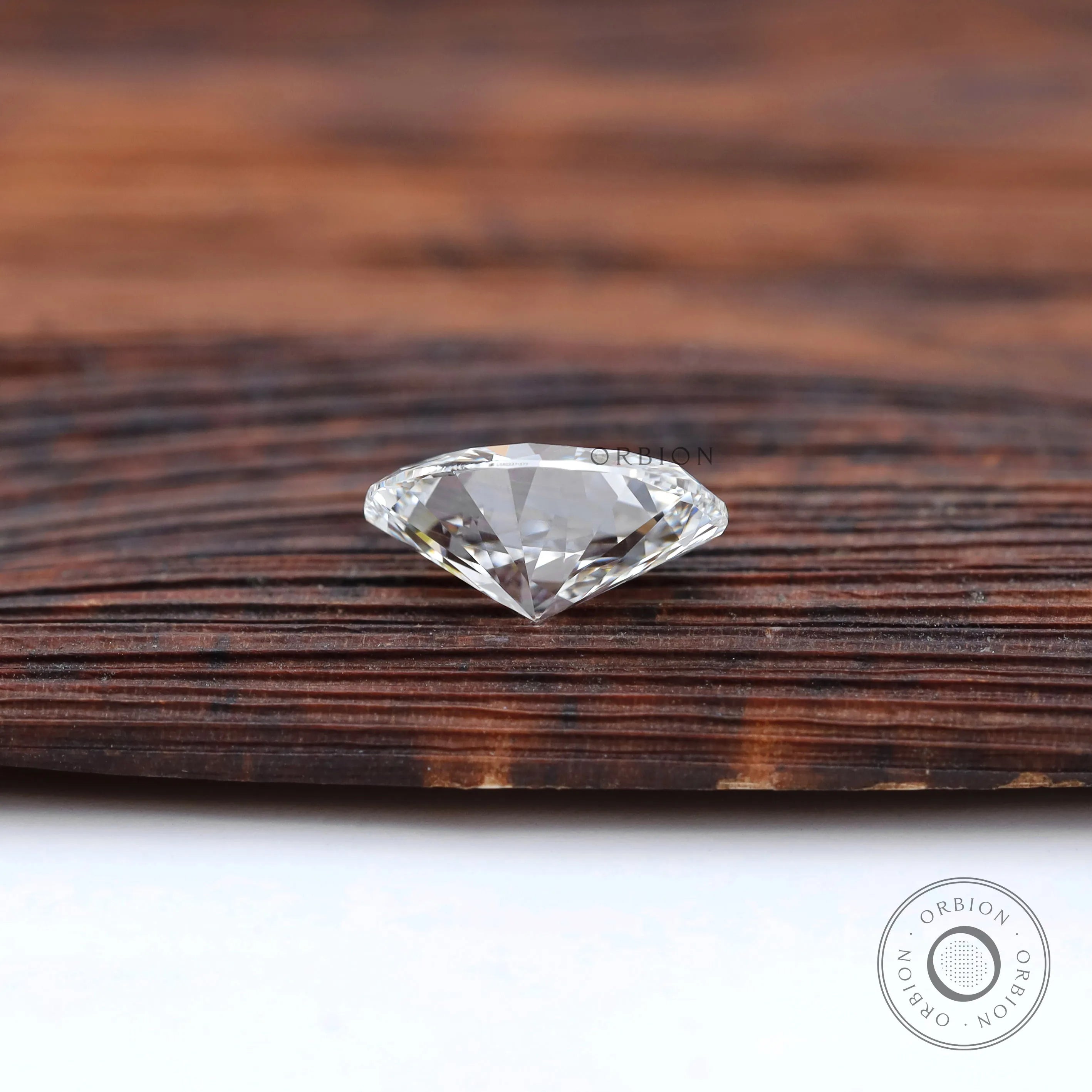 Brilliant cut oval loose diamond resting on wooden tray
